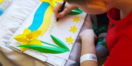 Powiększ grafikę: flaga Ukrainy z kolorowego papieru i wycięte z papieru żonkile z napisem w języku ukraińskim