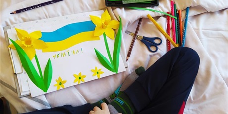 Powiększ grafikę: flaga Ukrainy z kolorowego papieru i wycięte z papieru żonkile z napisem w języku ukraińskim